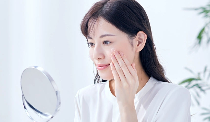 鏡で肌を確認する女性の写真
